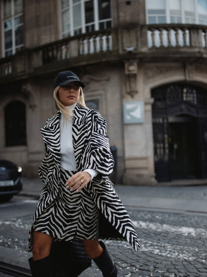 Manteau à motif zèbre chic blanc et noir. Col raffiné à rabat. Manches longues ballon avec plis élégants.