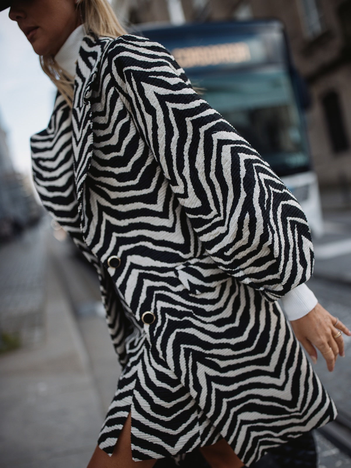 Manteau à motif zèbre chic blanc et noir. Col raffiné à rabat. Manches longues ballon avec plis élégants.